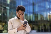 Un homme inquiet tient son téléphone et se couvre le visage