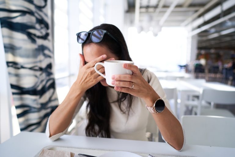 Une femme atterrée avec un café à la main