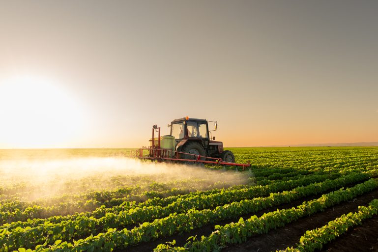 Un tracteur pulvérise des pesticides dans un champ