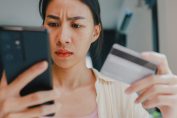 Une femme tient un smartphone et une carte de crédit