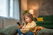 Une petite fille regarde la télévision en mangeant du pop-corn