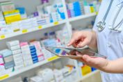 Un pharmacien utilise une tablette devant des médicaments dans une pharmacie