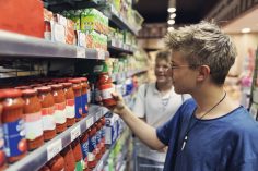Deux jeunes hommes choisissent de la sauce tomate dans un magasin