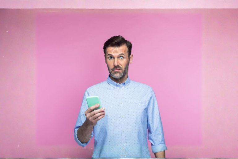Un homme surprise en regardant son smartphone