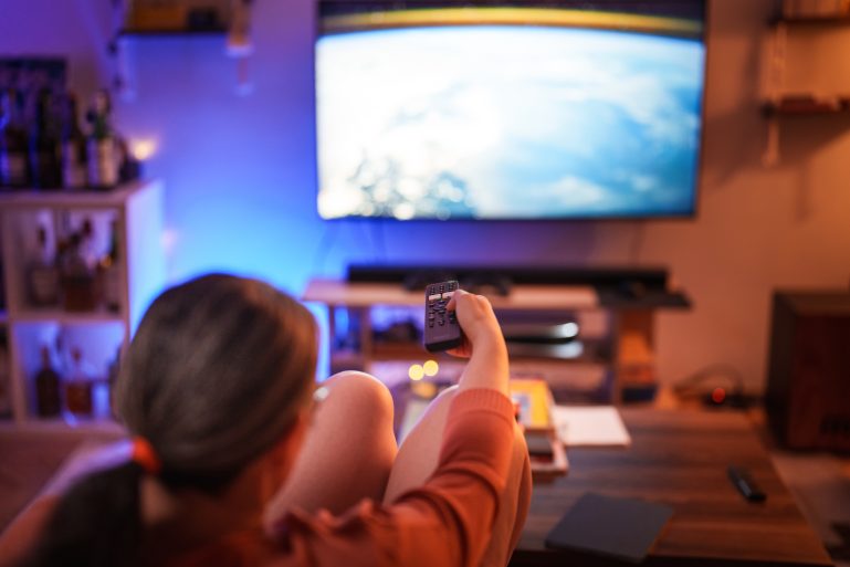 Une femme regarde la télévision avec une télécommande 