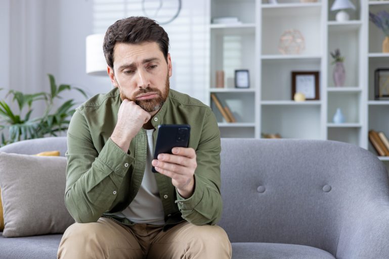 Un homme boude en regardant son téléphone