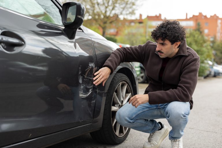 Un homme regarde les rayures sur sa voiture
