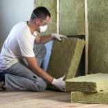 Un homme pose des panneaux d'isolation de laine de roche