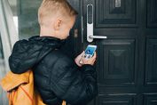 Un garçon utilise son smartphone pour ouvrir la porte de sa maison