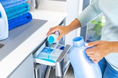 Un homme met de la lessive dans sa machine à laver