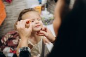 Une maman met du fard à paupière à sa petite fille