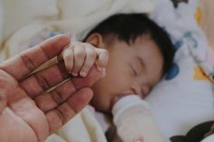 bébé buvant au bieront et tenant la main