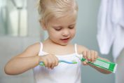 Une petite fille met du dentifrice sur sa brosse à denr