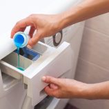 Une personne met de la lessive liquide dans sa machine