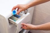 Une personne met de la lessive liquide dans sa machine