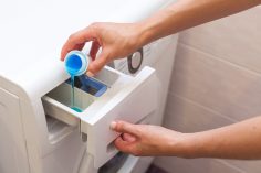 Une personne met de la lessive liquide dans sa machine