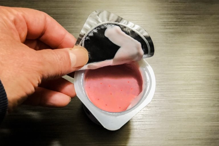Ouverture de la fraîcheur du yogourt aux fraises et d’un contenant en plastique à service unique