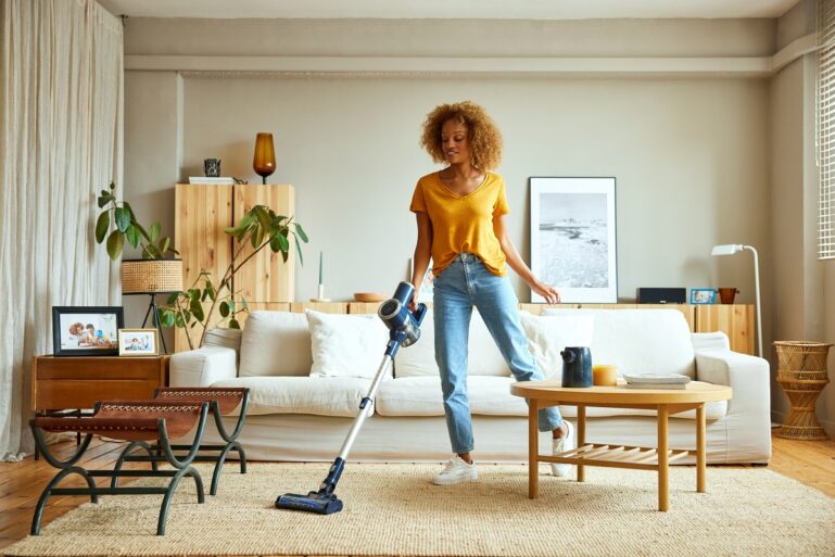 Une femme passe un aspirateur laveur sur un tapis.