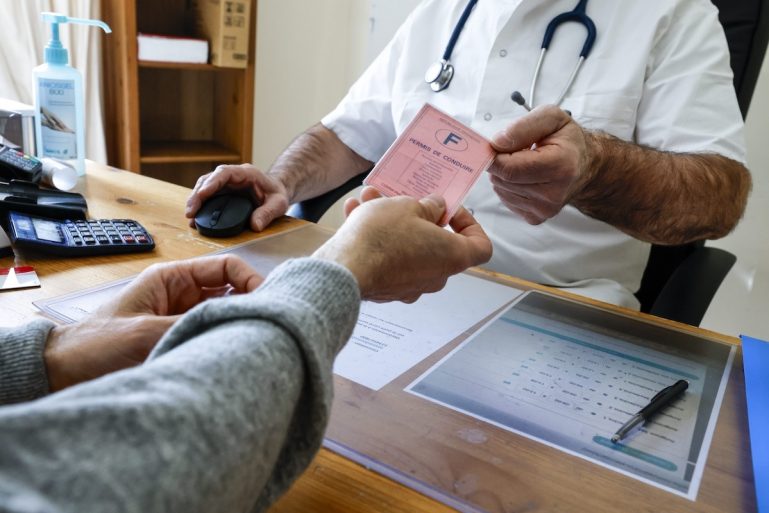 Un homme tend un permis de conduire à un médecin